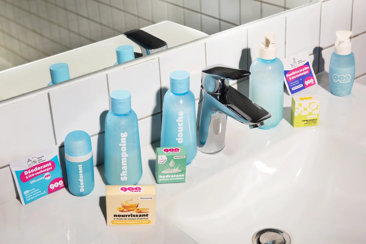 La gamme 900.care disposée sur un lavabo de salle de bain : déodorant, shampoing, gel douche, dentifrice et recharges
