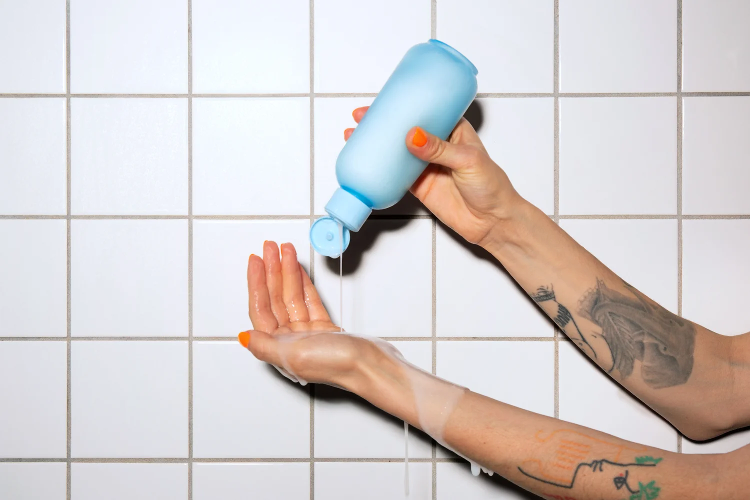 Une main verse du gel douche 900.care dans le creux de la main, sous la douche