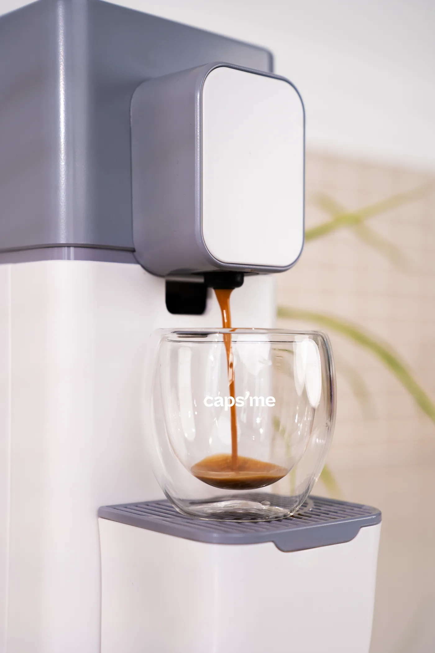 Un espresso à la belle crema coule dans un verre Caps'me depuis une machine à café