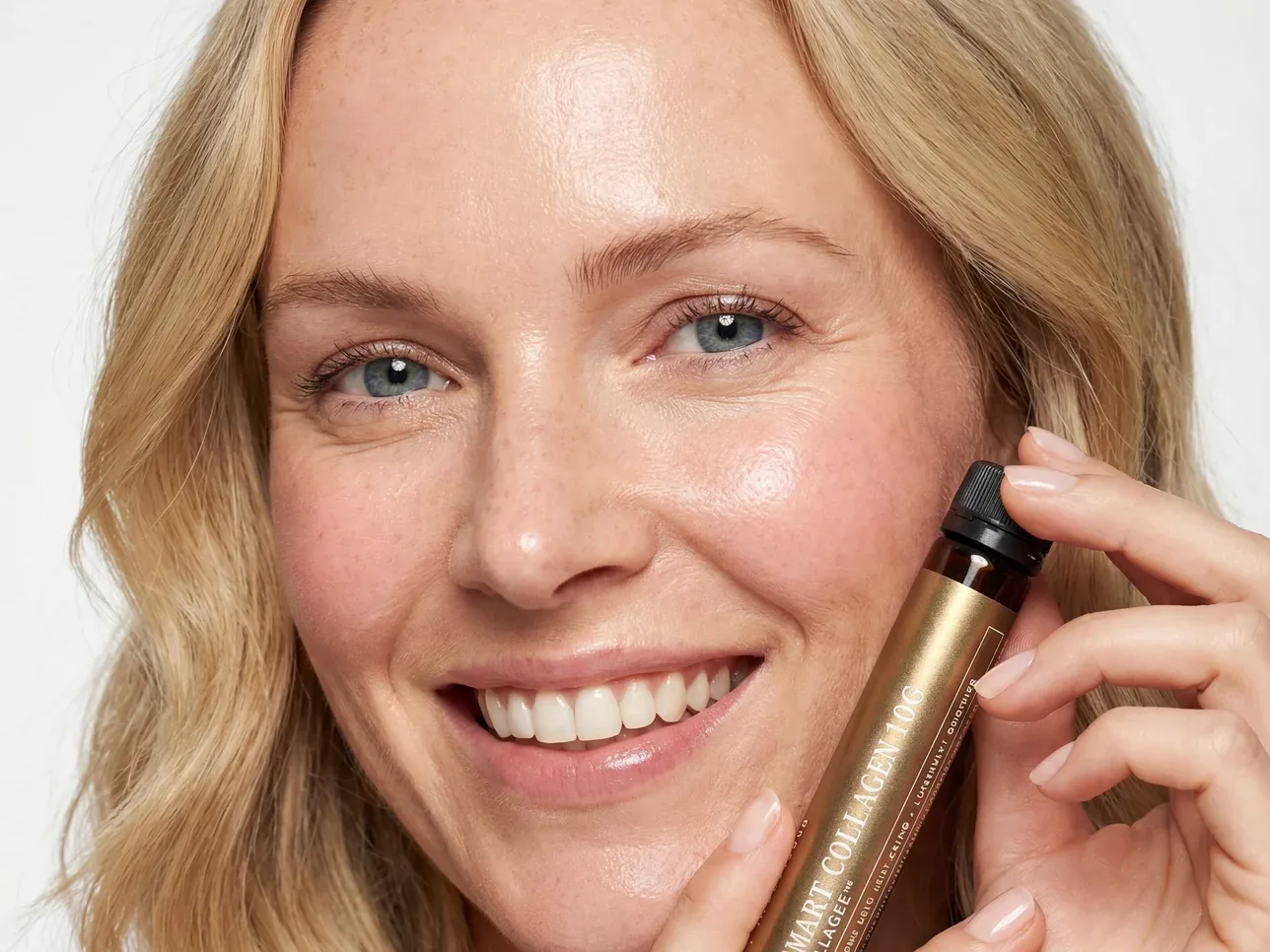 Une cliente Insentials souriante tenant un shot Smart Collagen 10g