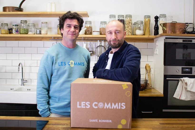 Les deux fondateurs des Commis dans leur cuisine, derrière un carton de livraison de la marque
