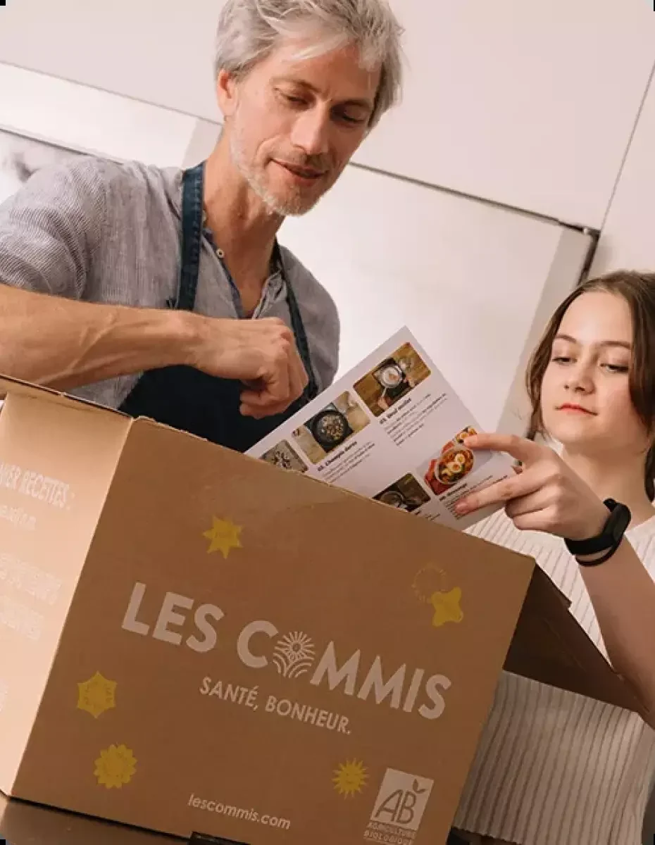 Un père et sa fille découvrent ensemble les fiches recettes dans le carton Les Commis qu'ils viennent d'ouvrir